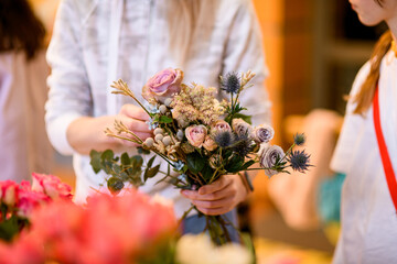 The female hands of the florist make a composition of different flowers