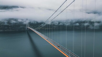 Hardanger bridge stretches across a vast expanse of ocean with clouds hovering over the side