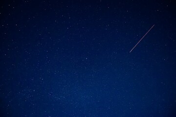an airplane flying through the dark blue night sky with stars