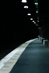 Wide shot of an abandoned subway station platform with lights illuminating the area