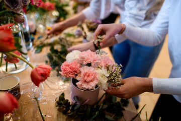 The female hands of two florists are engaged in arranging several beautiful bouquets of flowers