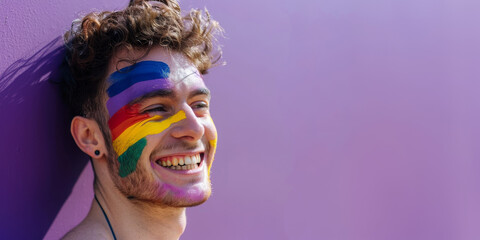 Happy smiling gay man, face painted with rainbow LGBT pride flag. LGBTQ celebration parade fun party, copy space for text