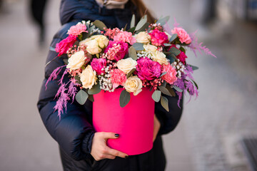 Female hands of a florist hold a bouquet of roses, carnations and white gypsophila