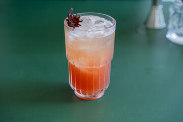 Coctail Drink with Red Color in a Big Glass with Rosella Flower on top as Garnish