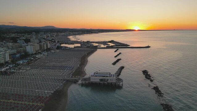 Drone rises to reveal the coast of Romagna Riviera with its sea at sunset in Italy