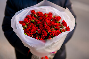 Close up of a huge bouquet of red roses in white and matte wrapping paper