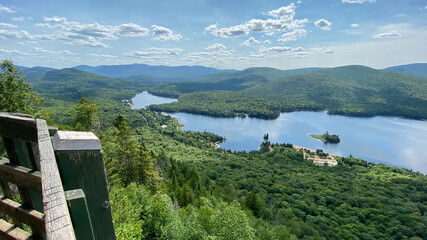 Naklejka premium Lake and mountains from a belvedere. High viewpoint of a valley in the mountains. Landscape of a river at the top of a mountain. Lookout point from a forest hike.