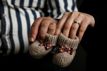 A close-up view of parents' hands holding knit baby socks