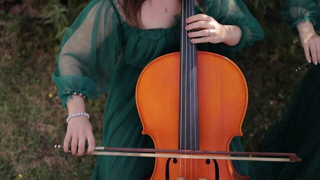 Elegant violoncellist female hands playing cello in the garden