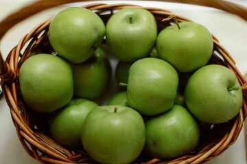 Closeup shot of a wicker basket with a pile of green apples
