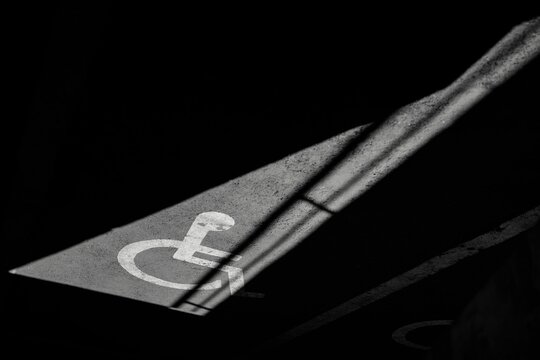 Grayscale closeup shot of a wheelchair symbol on the floor with shadows