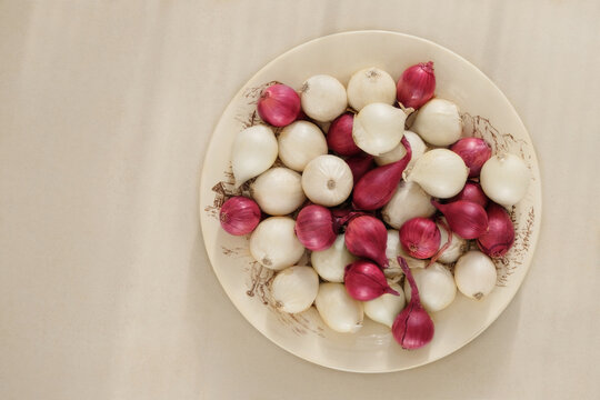 Onion in a clay plate on beige background. Salad purple and white onion in rustic bowl.