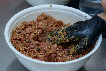 Bowl of freshly prepared food with a hand reaching in to be cooked