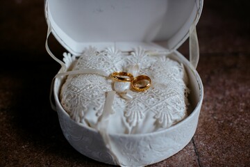 Gold wedding rings resting in a box with a white satin interior.