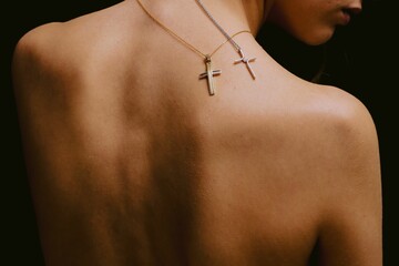Back view of a female wearing two cross necklaces.