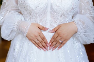 Close-up shot of a bride in a white wedding dress with her hands placed on her waist