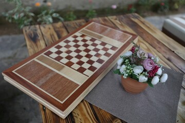 Backgammon board game atop a wooden table adorned with beautiful flowers