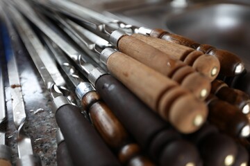 Collection of metal skewers with wooden handles, arranged in a neat row