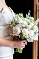 Beautiful bride with a graceful pose, holding a pristine bouquet of white flowers