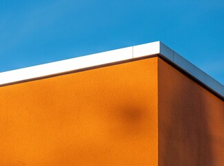 Exterior view of a corner of a building with bright orange walls set against a bright blue sky