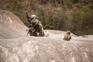 Soldiers in camouflage uniforms aiming with their rifles.ready to fire during military operation in...