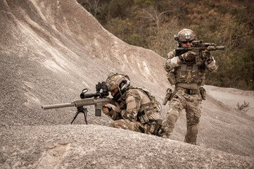 Soldiers in camouflage uniforms aiming with their rifles.ready to fire during military operation in...