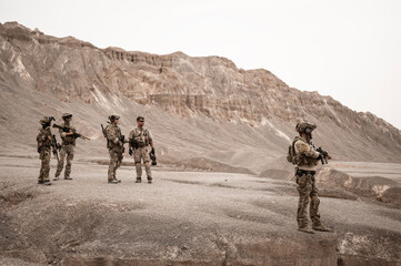 Soldiers in camouflage uniforms aiming with their rifles.ready to fire during military operation in the desert , soldiers training  in a military operation