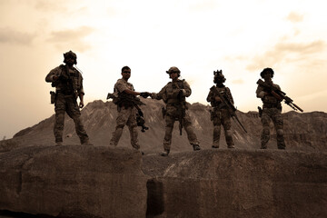 Soldiers in camouflage uniforms aiming with their rifles.ready to fire during military operation in...