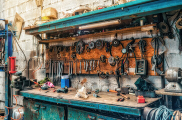 Vintage workshop. Antique tools hang on the wall, repair equipment on the table. Side view.