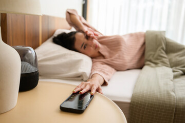 Sleeping asian woman turning off alarm on smartphone while being Waken up in the morning - obrazy, fototapety, plakaty