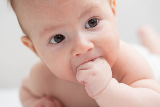 A little caucasian boy aged three years old sucks his fists in his mouth. The concept of the sucking reflex in children.