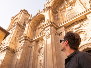 Caucasian man tourist wearing sunglasses in front of the cathedral in Granada Spain looking up with copyspace - 768850681