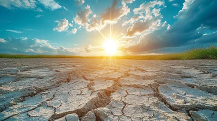 Foto op Aluminium cracked earth during a drought with a bright sun in the background © Du