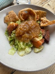 roast pork belly with apple sauce crackling and hispi cabbage on white plate on wood table