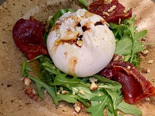 burrata Italian cows milk cheese salad with crispy fried parma ham crushed walnuts and dressed with olive oil and balsamic (Burrata is combine mozzarella and cream)