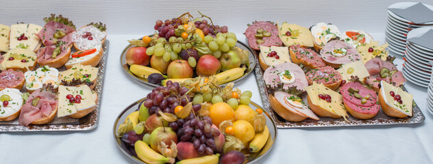 Diverse belegte Brötchen zum Frühstücken mit einer Obstschale