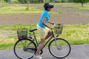woman with virtual reality goggles cycling in nature. Virtual reality concept.
