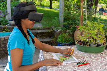 A multiracial woman in VR glasses designs a garden at a table.