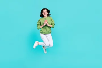  Full body portrait of pretty excited person hold telephone enjoy free time isolated on teal color background © deagreez