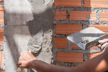 Hand plaster plastering with trowel wet cement wall brick masonry background construction site 