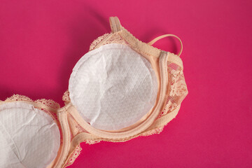Women's bra with liners against the flow of milk from the breast of a nursing woman on a pink...