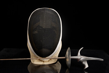 Front view of fencing sport mask and foil on black background - obrazy, fototapety, plakaty
