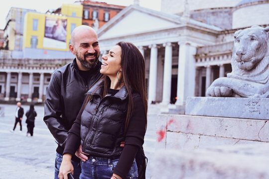 Happy smiling beautiful  Tourists  couple traveling at  Naples Italy, poses and making photos  in front of  Piazza del Plebiscito , Italy.Concept of Italian gastronomy and travel. Italian couple 