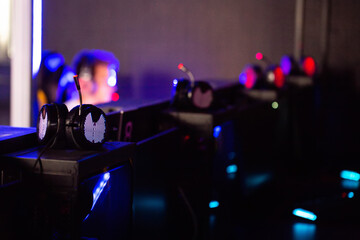 Headphones in focus in a computer club with players in the background. Concept of a tournament and playing computer games. Copy space for text