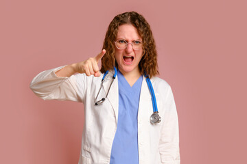 Furiously screaming female doctor, studio pink background. Nurse in uniform with stethoscope on red studio background