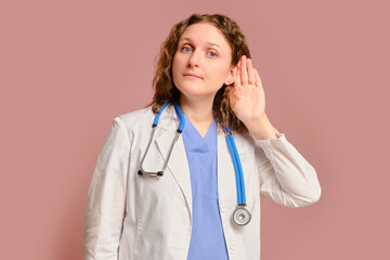 Woman doctor listen gesture, studio pink background. Nurse in uniform with stethoscope on red studio background