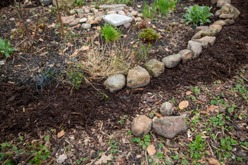 Mit Natursteine eine Blumenbeet einfassen.