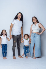 young latin family of father mother and two daughters, having fun posing and smiling, studio shot