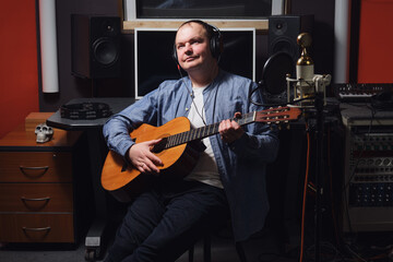 Obraz premium Happy musician with a smile on his face in a recording studio. Workplace of a sound engineer in a recording studio