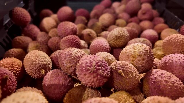 Organic lychee fruit, Litchi chinensis, on market.
Slow panning shot with selective focus.